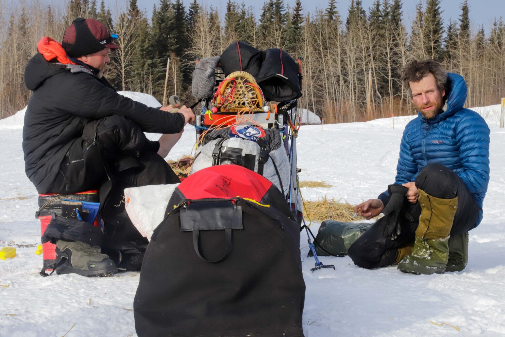 Two people talking near a dog sled