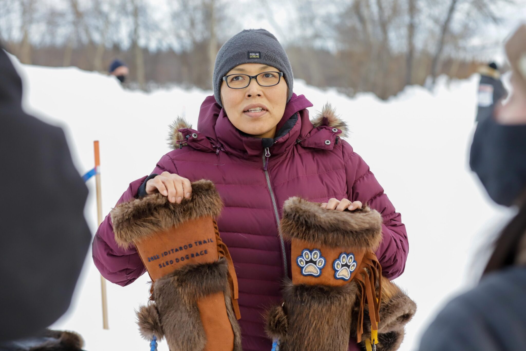 a person holds a pair of beaded and fur mittens