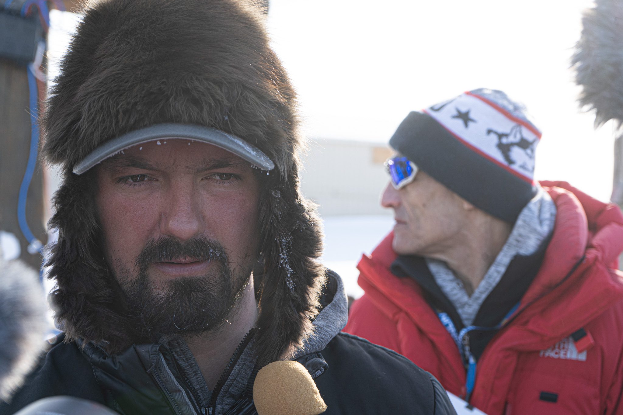 A man in a fur baseball hat and a small beard