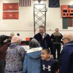 smiling man greets people in a gymnasium