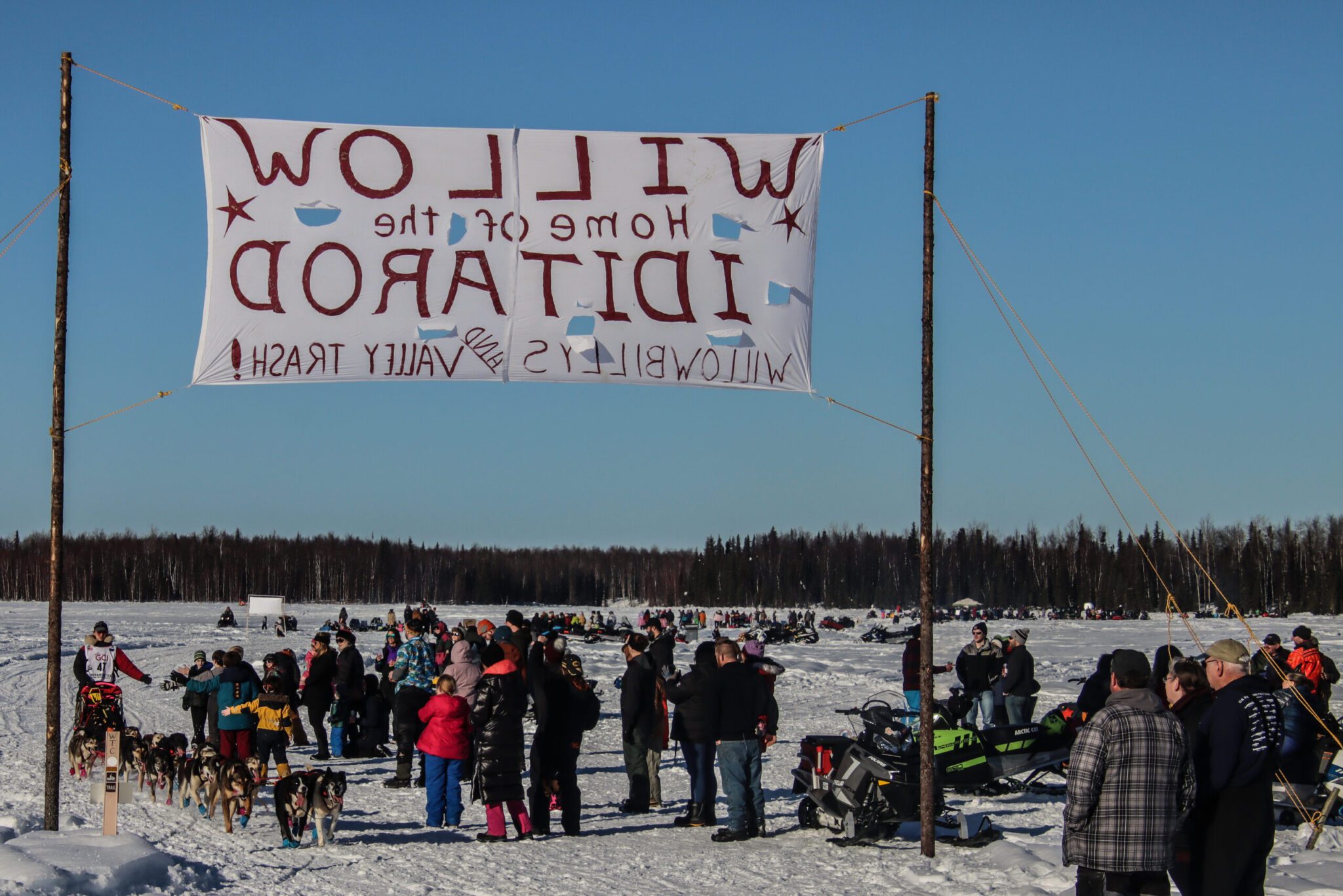 A dog team passes under a banner on a frozen open lake