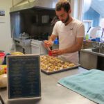 Thomas puts an egg wash on his signature Swedish cinnamon rolls. (Photo: Maddie Winchester, KNOM)