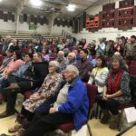 people seated in a gymnasium watch something