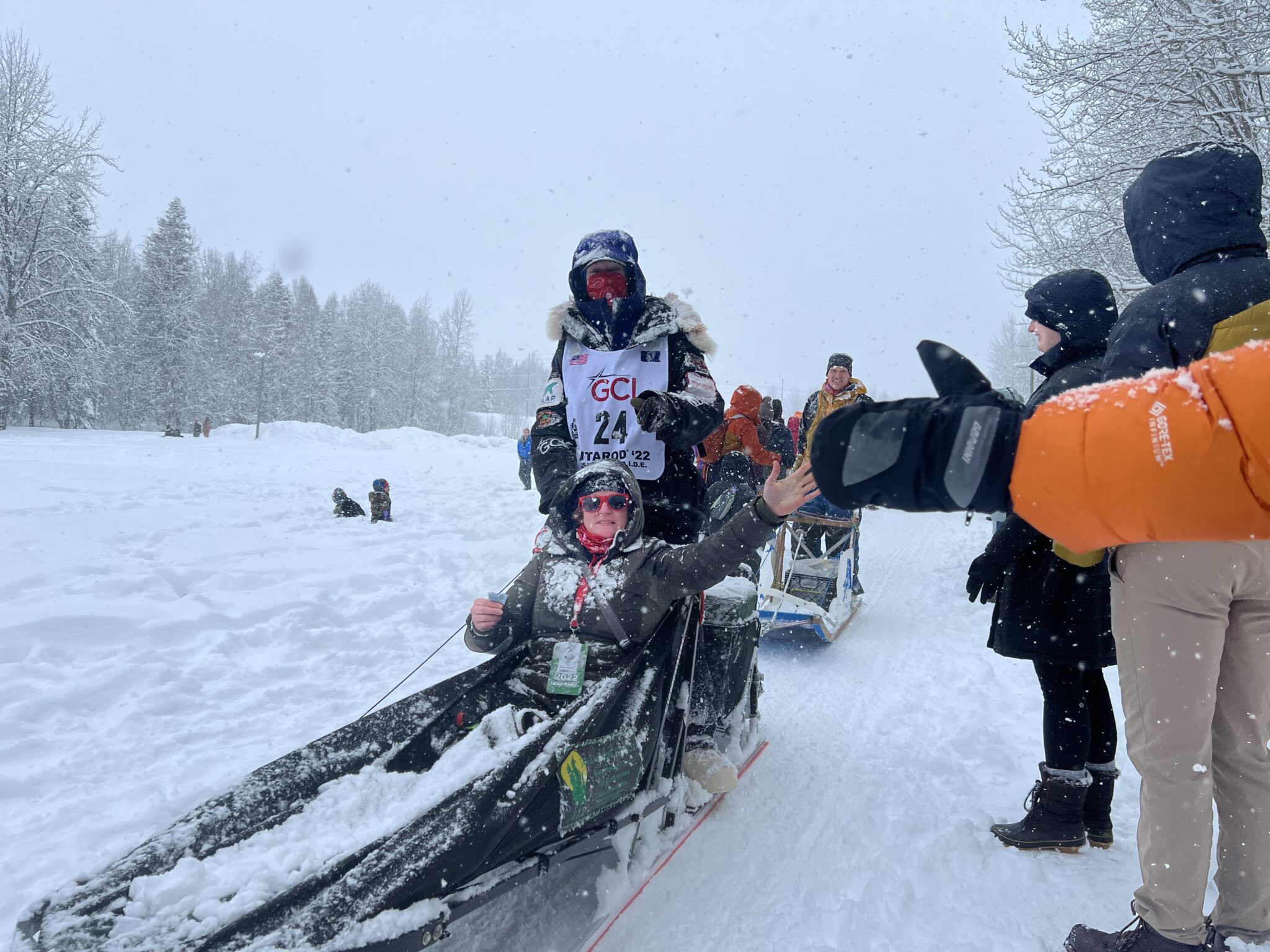 A person in a sled gives high fives