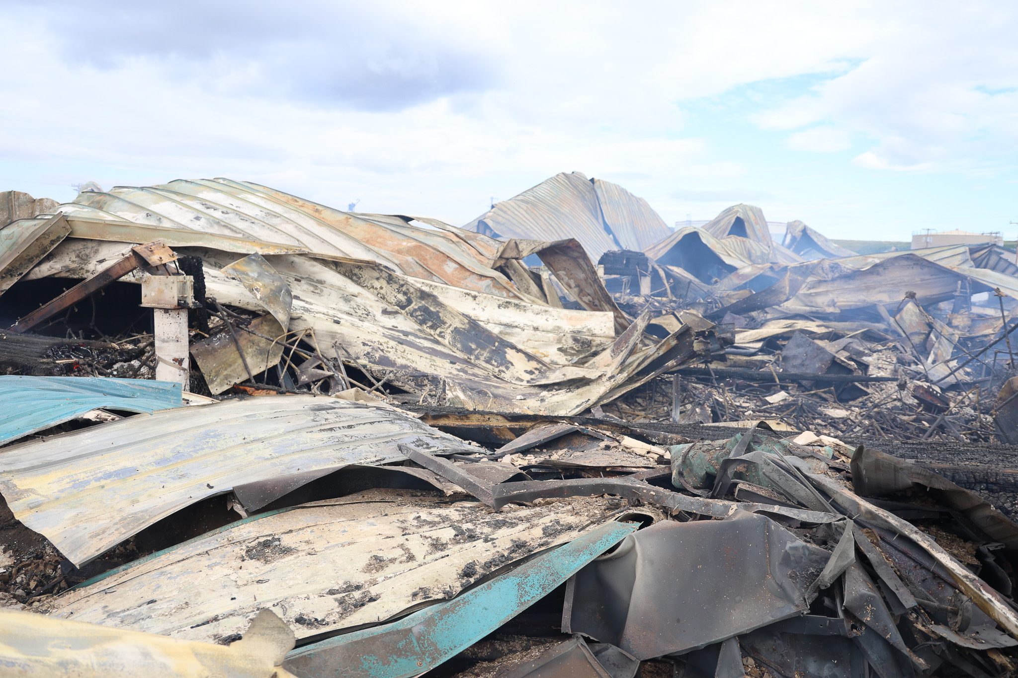 Warped metal roofing lies on the ground as smoke emerges from the ruins of Stebbins School. Ben Townsend photo.