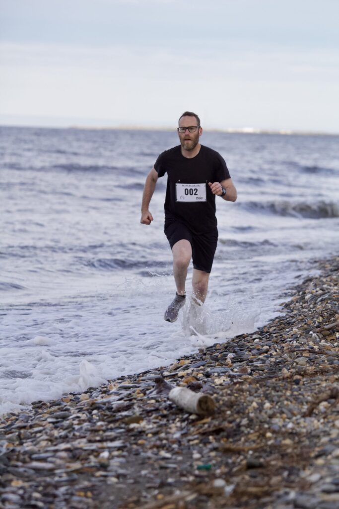 Patrick Landback runs through water on the shoreline of Nome during the Gold Dust Dash. Ben Townsend photo.