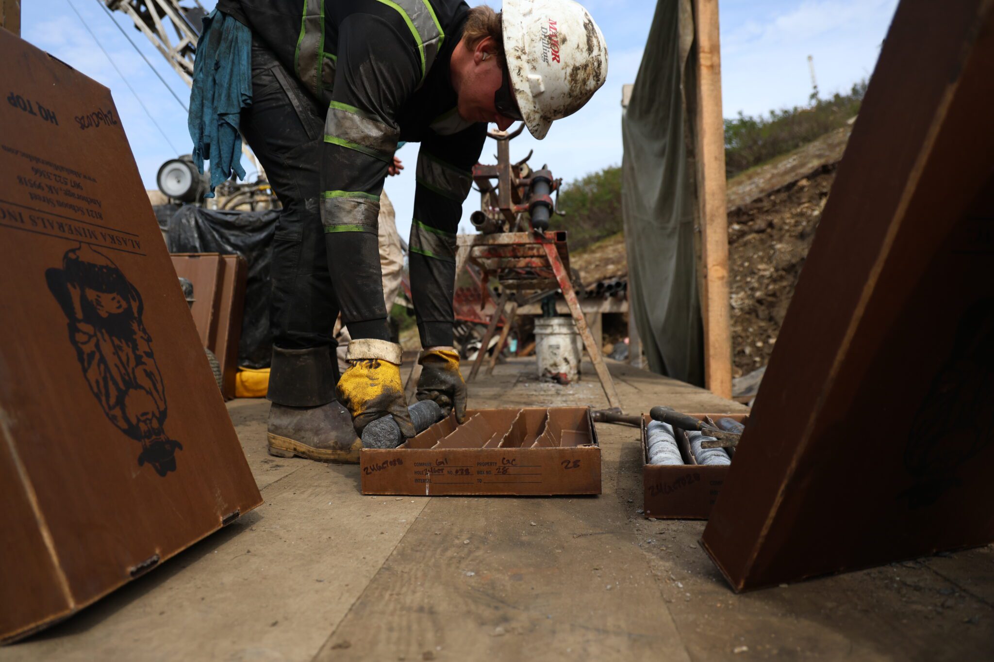 A drill operator lays a fresh core sample in a core box.