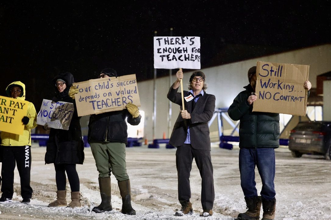 Nome Elementary School Teacher Ian McRae holds a white sign that reads "THERE'S ENOUGH FOR TEACHERS". Ben Townsend photo.