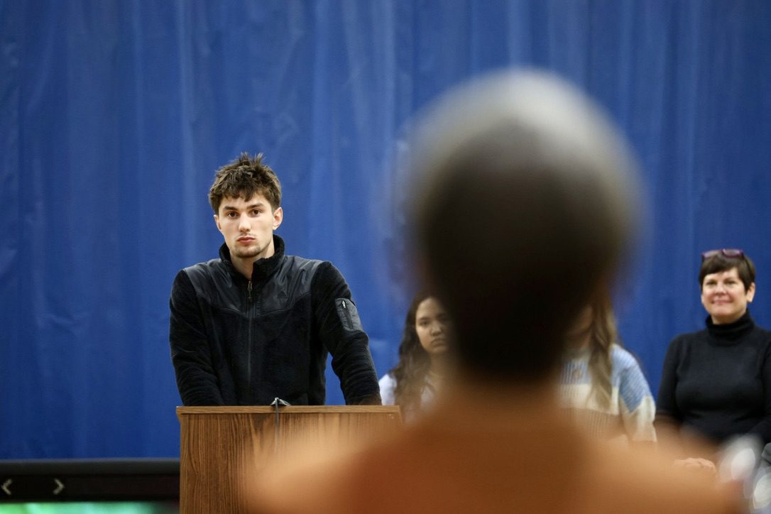 Finn Gregg at the lectern with Justice Susan M. Carney in the foreground. 