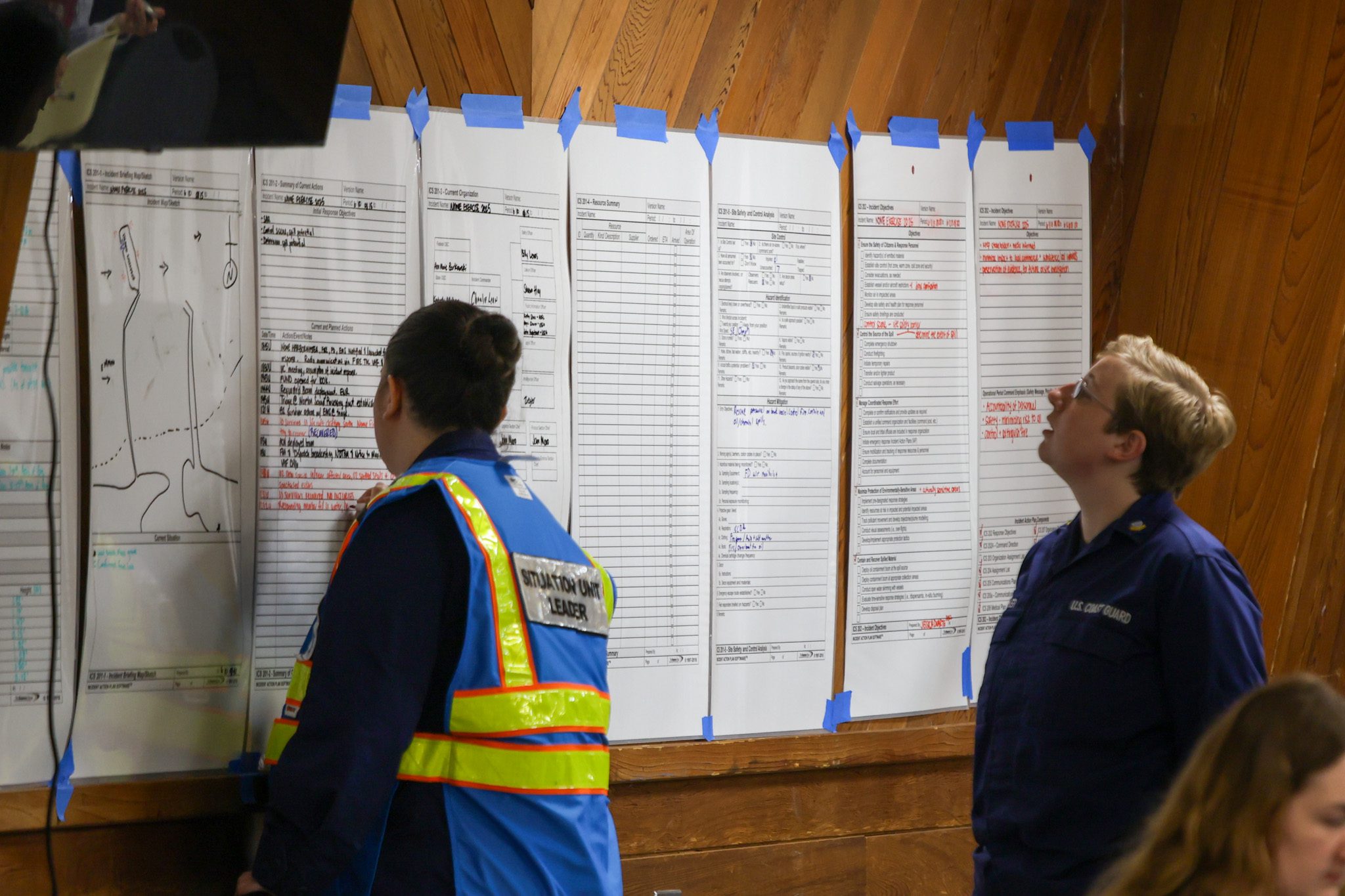 IMG_7256 Participants in an oil spill response drill study paper checklists pinned to the wall of Nome's Mini Convention Center. Wali Rana photo.
