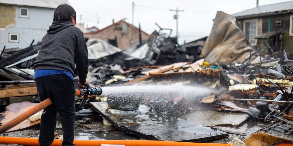 Children could be seen taking turns on fire hoses as the remains smoldered. Ben Townsend photo.