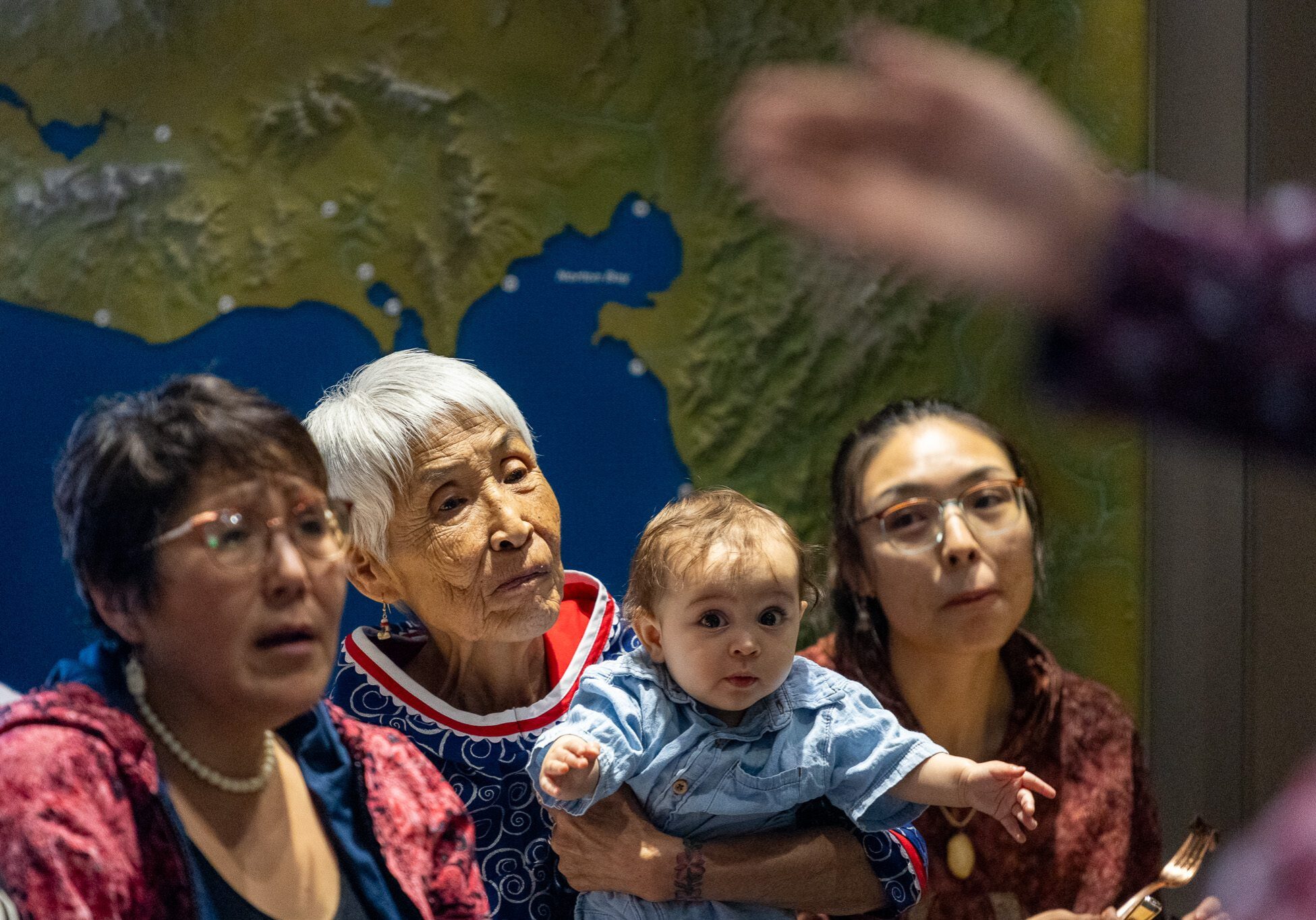 102A0539 Maria Dexter holds her great-grandson on her lap as drummers and dancers perform. Ben Townsend photo.