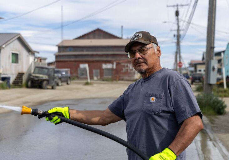 Aaron Jackson holds a hose toward Steadman Street in Nome. Ben Townsend photo.