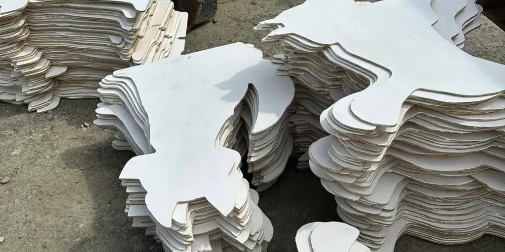 Cardboard sled dog cutouts sit stacked on the ground. The white wood figures will soon be colorfully decorated for the Sled Dogs on Parade event. Photo courtesy NSHC.