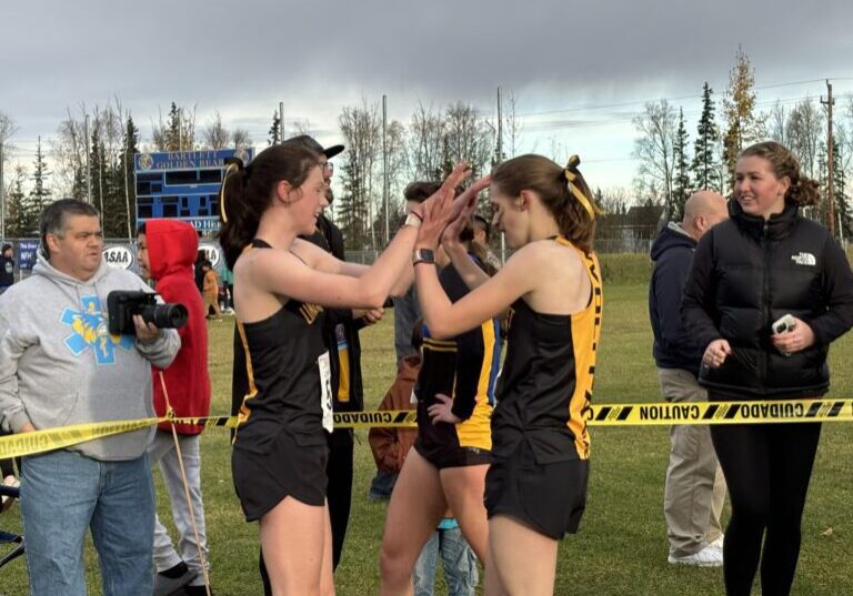 Unalakleet's Ourea Busk high-fives teammate Isabella Eller near the finish line of the Division II Cross Country State Championships. Janice Homekingkeo photo. 