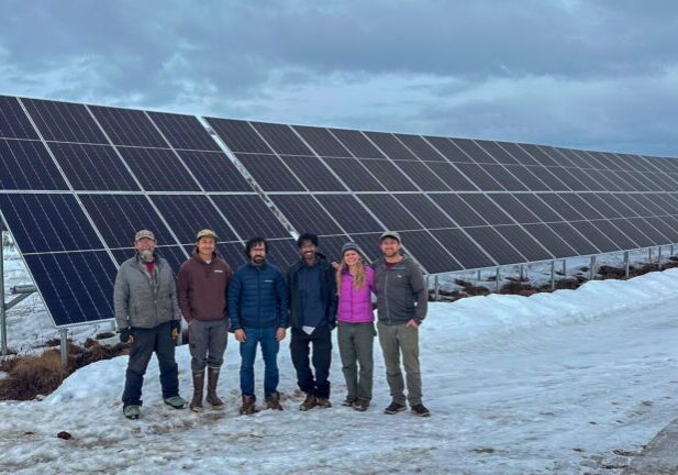 Brad Scotton, board member of Sustainable Energy for Galena, Alaska (SEGA), posing next to solar panels with the REAP team. Photo courtesy of Haleigh Reed. 