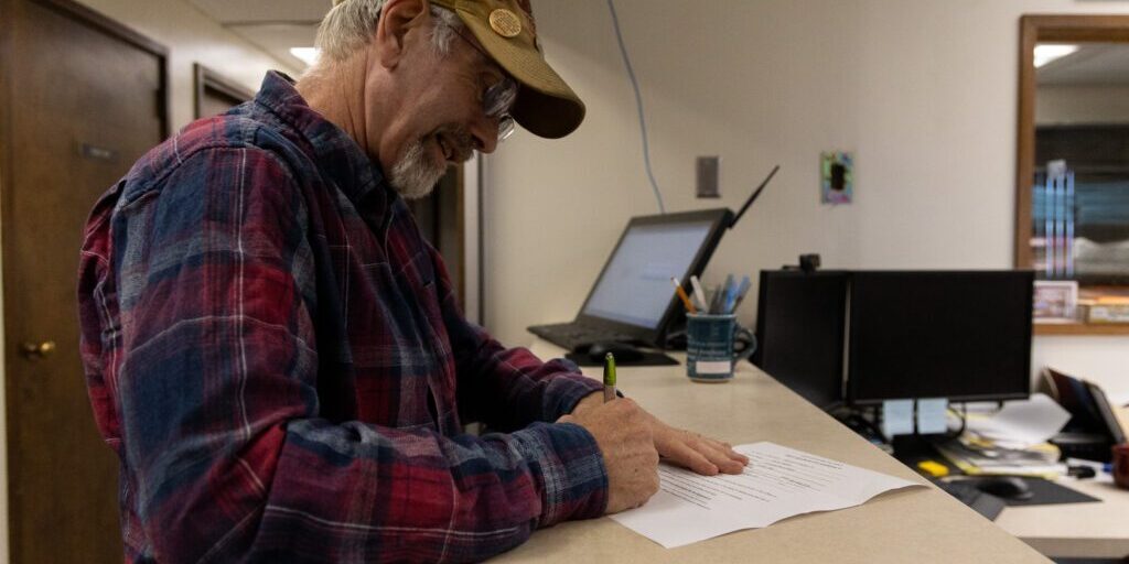 Kenny Hughes signs filing paperwork for the mayor of Nome position at City Hall on Sept. 2, 2025. Ben Townsend photo.